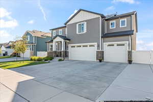 View of front of house with board and batten siding, a garage, concrete driveway, and stone siding