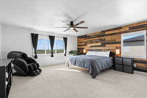 Primary bedroom featuring wooden walls, carpet, a textured ceiling, and a ceiling fan