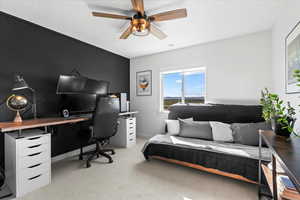 Bedroom/additional office with a desk, light carpet, and ceiling fan
