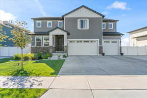 Craftsman Two-Story house with an attached garage, driveway, stone siding, and board and batten siding