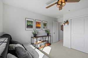 Bedroom/additonal office with light carpet and a ceiling fan