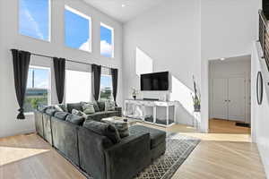 Living room with a towering ceiling, healthy amount of natural light, wood finished floors