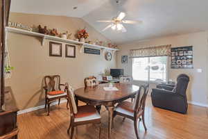 Dining space featuring a ceiling fan, vaulted ceiling, light wood-type flooring, and baseboards