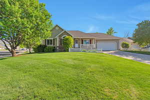 Ranch-style house featuring an attached garage, a porch, a front yard, driveway, and stucco siding