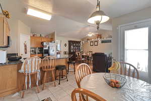 Dining space with ceiling fan, light tile patterned floors, and lofted ceiling
