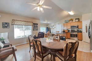 Dining room featuring a ceiling fan, lofted ceiling, light wood-type flooring, and baseboards
