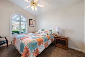 Bedroom with carpet floors, vaulted ceiling, baseboards, and ceiling fan
