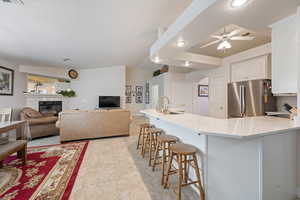 Kitchen featuring freestanding refrigerator, a sink, a breakfast bar, a ceiling fan, and white cabinetry