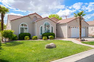 Mediterranean / spanish home featuring an attached garage, a front yard, a tile roof, and stucco siding