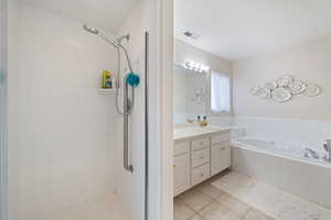 Full bathroom featuring tile patterned floors, a tile shower, a bath, and vanity