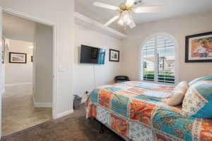 Carpeted bedroom with baseboards, a ceiling fan, and tile patterned flooring