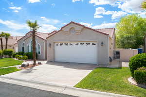 Mediterranean / spanish-style home featuring a tiled roof, an attached garage, driveway, stucco siding, and a gate