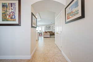 Hallway with arched walkways, light tile patterned floors, and baseboards