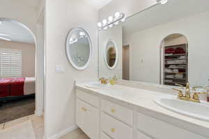 Ensuite bathroom with tile patterned flooring, double vanity, a walk in closet, and baseboards