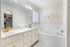 Bathroom featuring tile patterned flooring, a garden tub, double vanity, and a walk in closet