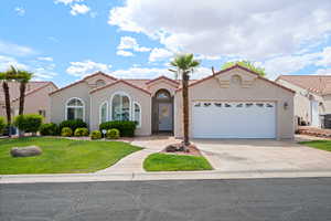 Mediterranean / spanish house with stucco siding, a garage, driveway, a front lawn, and a tiled roof