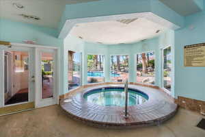 Indoor pool featuring an in-ground hot tub