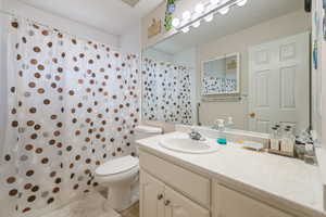 Bathroom with toilet, vanity, curtained shower, and tile patterned floors