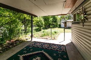 View of patio with a storage unit, fence, and an outdoor structure