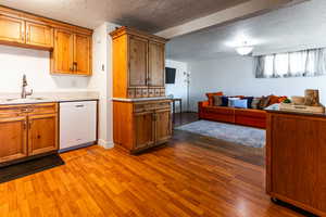 Kitchen with white dishwasher, a sink, and brown cabinetry