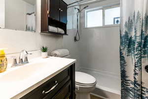 Full bathroom with a shower with shower curtain, toilet, and vanity