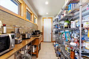 Kitchen featuring a sink, stainless steel microwave, backsplash, recessed lighting, and tile patterned flooring