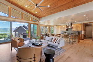Living area with a towering ceiling, light wood-style floors, recessed lighting, ceiling fan, and wooden ceiling