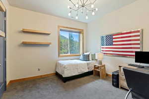 Bedroom featuring carpet, a chandelier, baseboards, and an office area