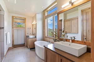 Full bath with a freestanding bath, tile patterned floors, and two vanities