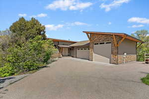 View of front of property with stone siding, a garage, and driveway