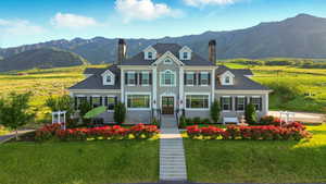 Colonial home with a chimney, a mountain view, and a front yard