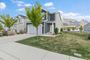 Traditional-style house featuring board and batten siding, concrete driveway, a mountain view, and a front lawn