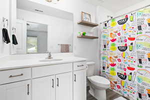 Full bath with toilet, vanity, wood finished floors, and a shower with shower curtain