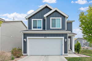 Traditional-style house featuring board and batten siding, concrete driveway, and an attached garage