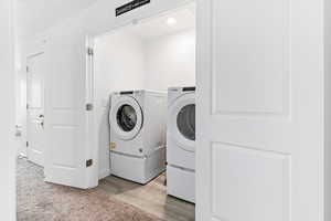 Laundry room featuring washing machine and dryer, light wood finished floors, and baseboards