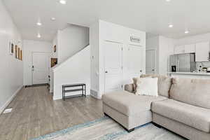 Living room with recessed lighting, light wood-type flooring, baseboards, and stairs