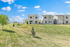 Rear view of house featuring stucco siding and a lawn
