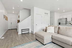 Living area featuring recessed lighting, light wood finished floors, baseboards, and stairs