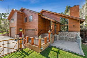 Back of property featuring an attached garage, a chimney, fence, concrete driveway, and a gate