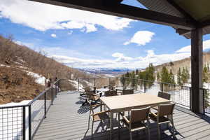 Snow covered deck featuring a mountain view and outdoor dining area
