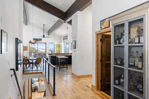 Corridor with baseboards, wood finished floors, high vaulted ceiling, and recessed lighting