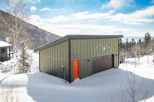 Snow covered garage featuring a garage and a mountain view