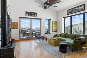 Living room with ceiling fan, high vaulted ceiling, hardwood / wood-style flooring, a wood stove, and recessed lighting