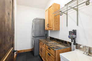 Laundry area featuring stacked washer / dryer and cabinet space