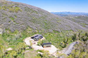 Aerial view of property and surrounding area with mountains and a heavily wooded area