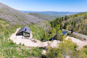 Aerial view of property and surrounding area with a mountain backdrop and a heavily wooded area
