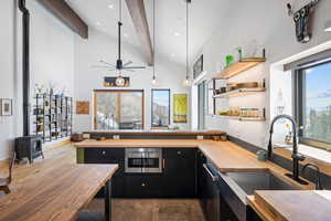 Kitchen featuring butcher block counters, a sink, dark cabinetry, wood finished floors, and beam ceiling