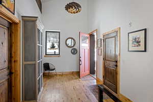 Entrance foyer with light wood-type flooring, a towering ceiling, and baseboards