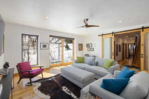 Living area featuring a barn door, light wood finished floors, a ceiling fan, and recessed lighting