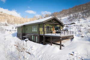 Snow covered rear of property featuring a deck